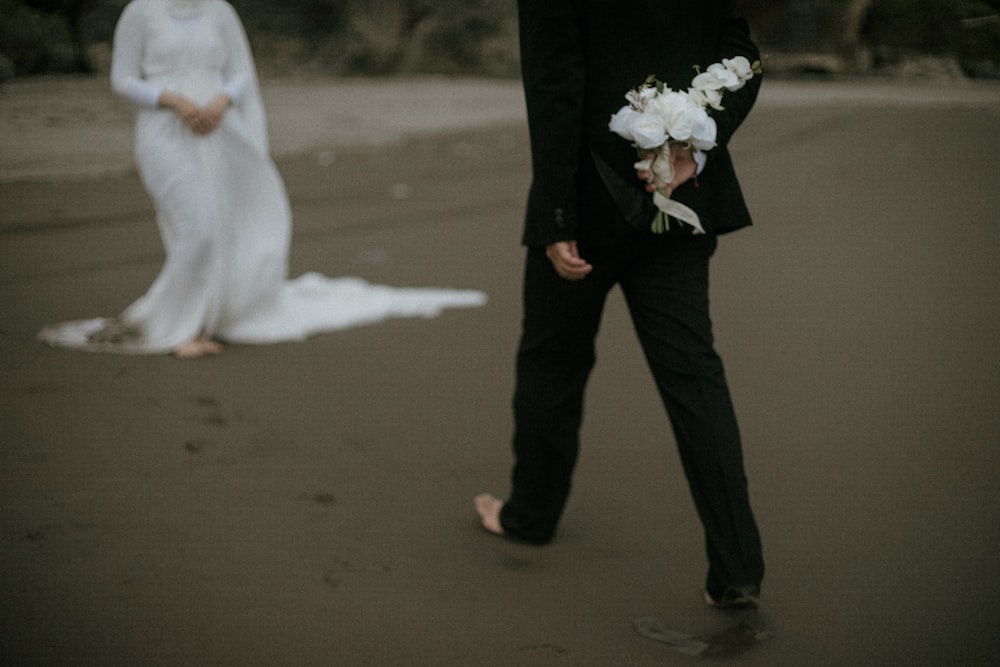 a bride and groom walking on the beach