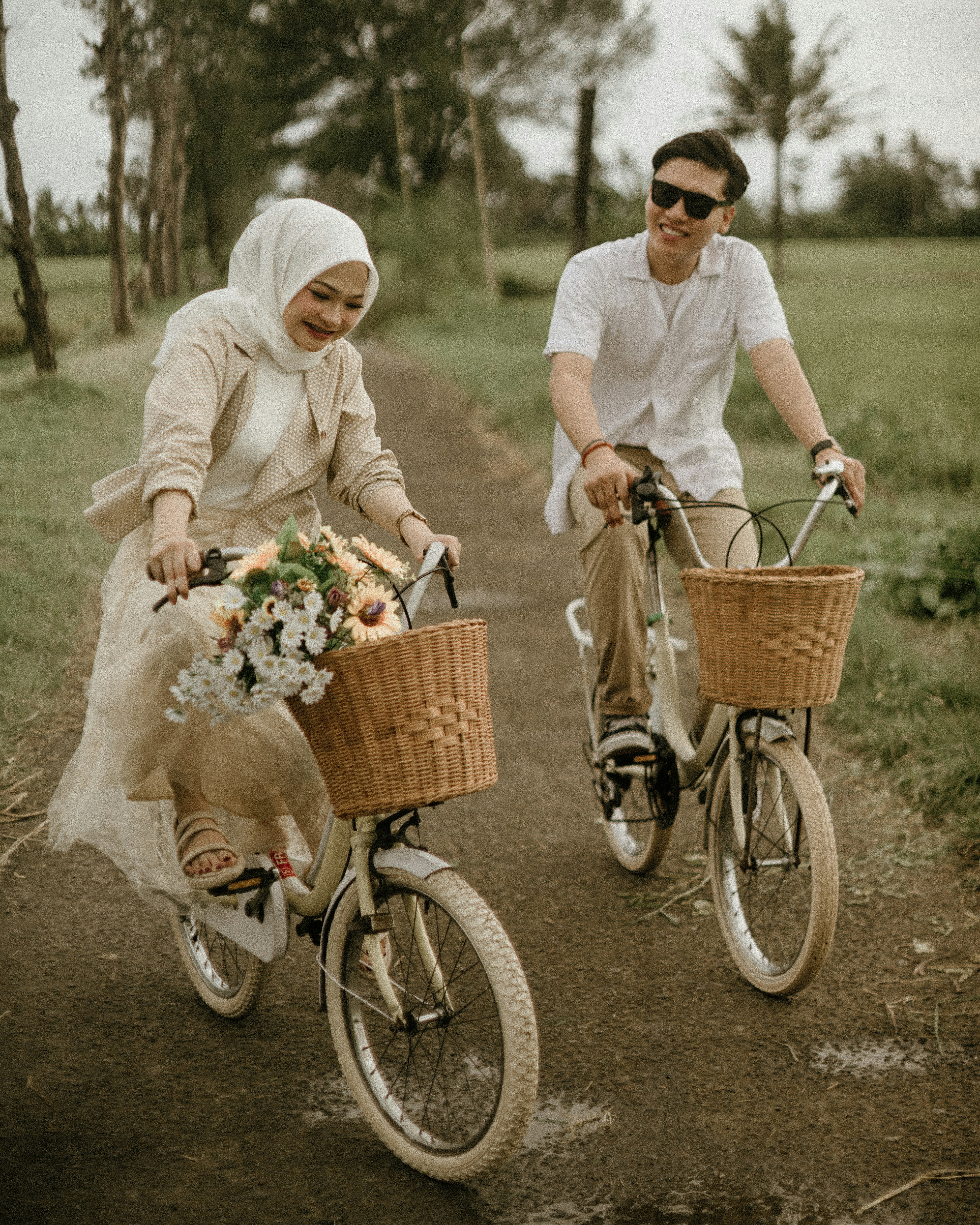 a man and a woman riding bikes down a dirt road