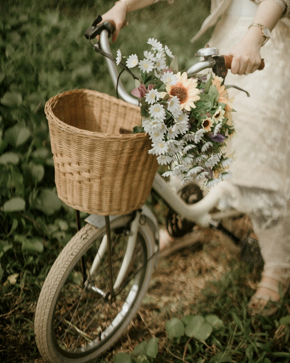 a woman riding a bike with a basket full of flowers
