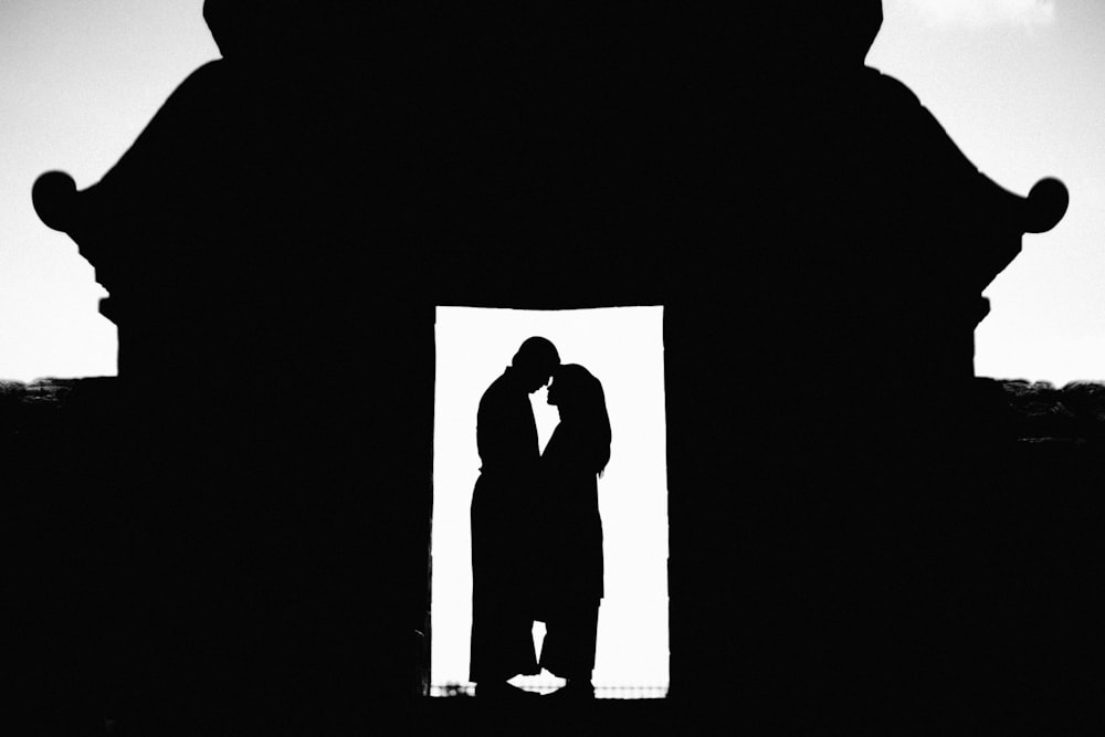 a silhouette of a man and woman kissing in front of a building