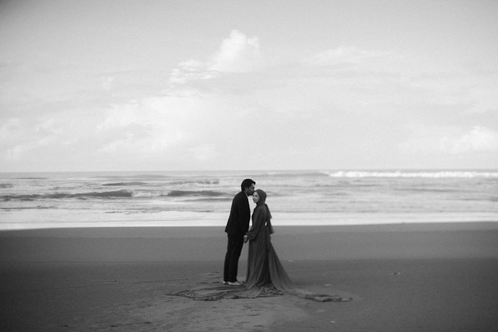 a black and white photo of a couple on the beach