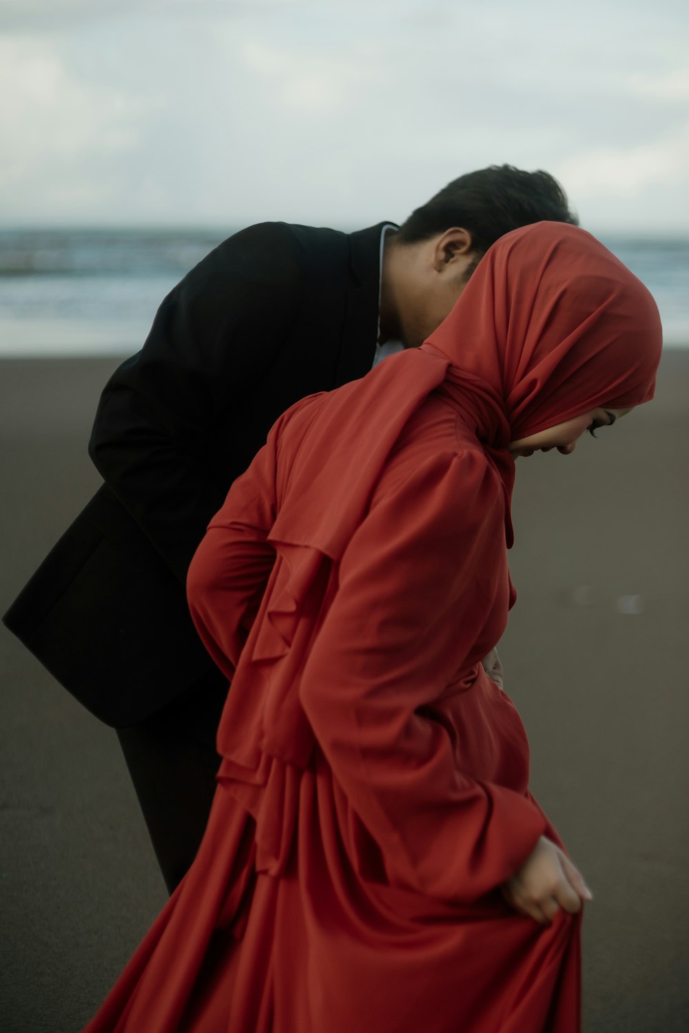 a woman in a red dress standing next to a man in a black suit