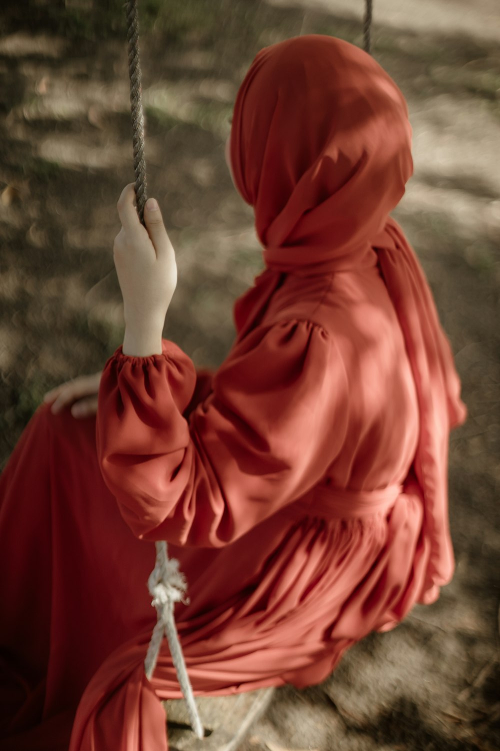 a woman in a red dress sitting on a swing