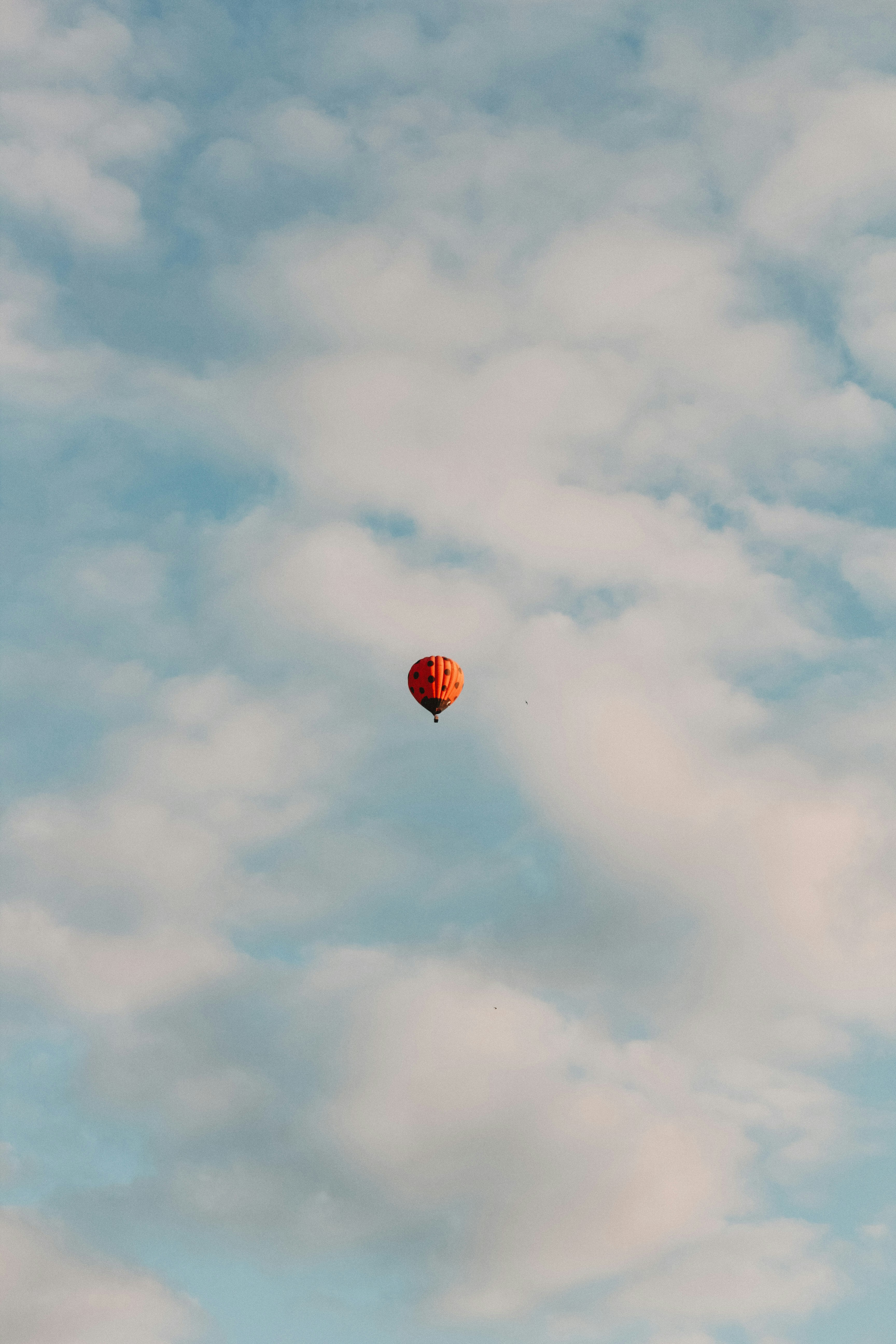 Hot air balloon flying through cloudy blue sky