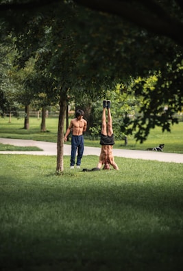 a man and a woman doing a handstand in a park