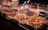 A variety of nuts and dried fruits are displayed in transparent containers at a market or store. Each section is labeled with its specific mix, and metal scoops are placed on the side for serving. The selection includes almonds, raisins, and other mixed nuts.