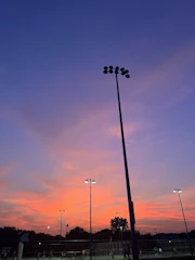 A vibrant outdoor sports event with dynamic lighting and large LED screens at sunset.