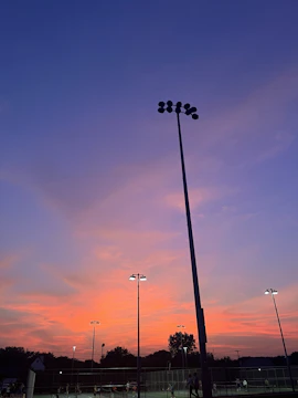 A vibrant outdoor sports event with dynamic lighting and large LED screens at sunset.