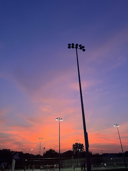 A vibrant padel court bathed in warm sunset light, with players mid-game showing dynamic action.