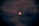 A red moon partially obscured by dark clouds in a night sky, creating an eerie and mystical atmosphere.