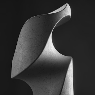 Abstract geometric sculpture displayed outdoors with natural light highlighting its contours.