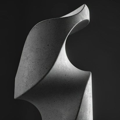 A smooth, abstract sculpture with flowing curves crafted from stone or concrete. The lighting emphasizes its textured surface and highlights the elegant, aerodynamic design against a dark background.