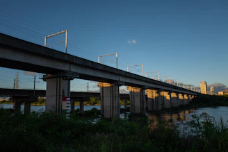 Sunset view of a completed concrete railway bridge with trains passing.