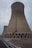 A well-maintained cooling tower with visible spare parts in place under a clear sky.