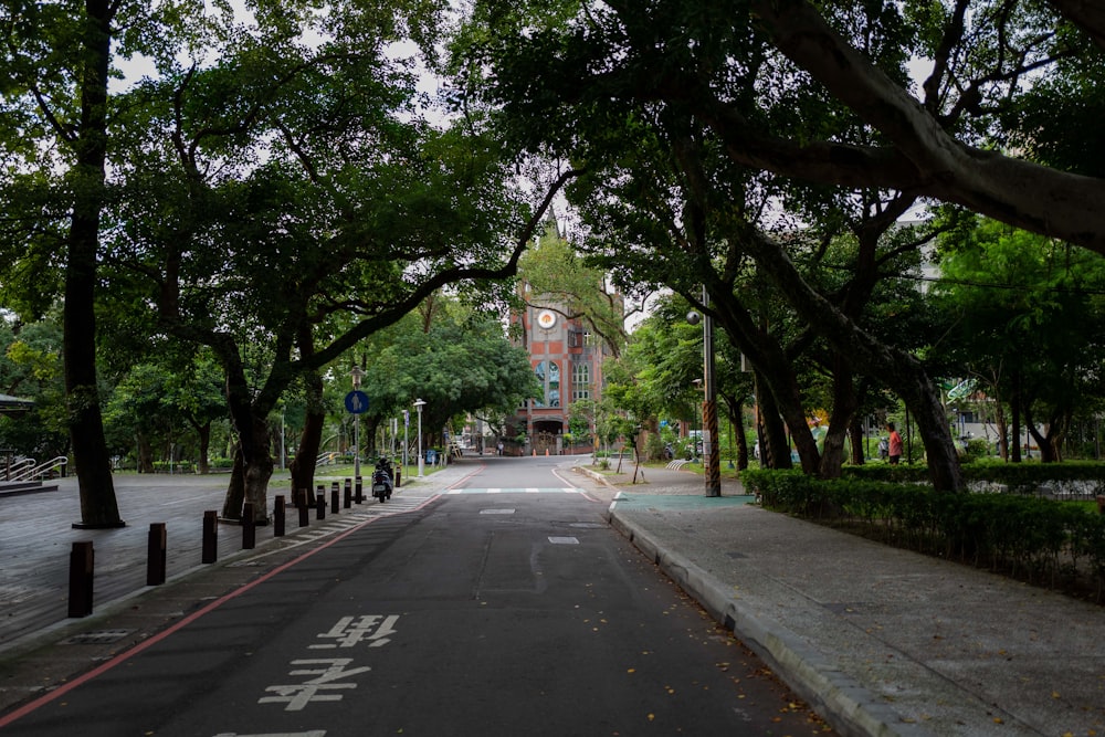 a street lined with trees with a clock tower in the background