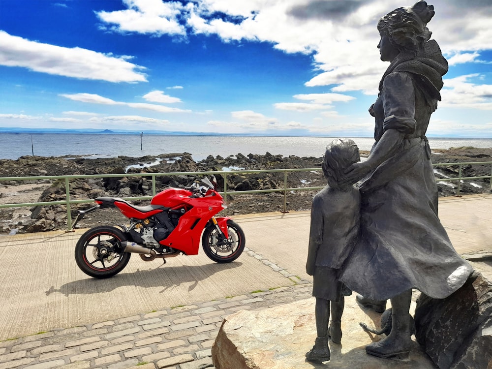a red motorcycle parked next to a statue