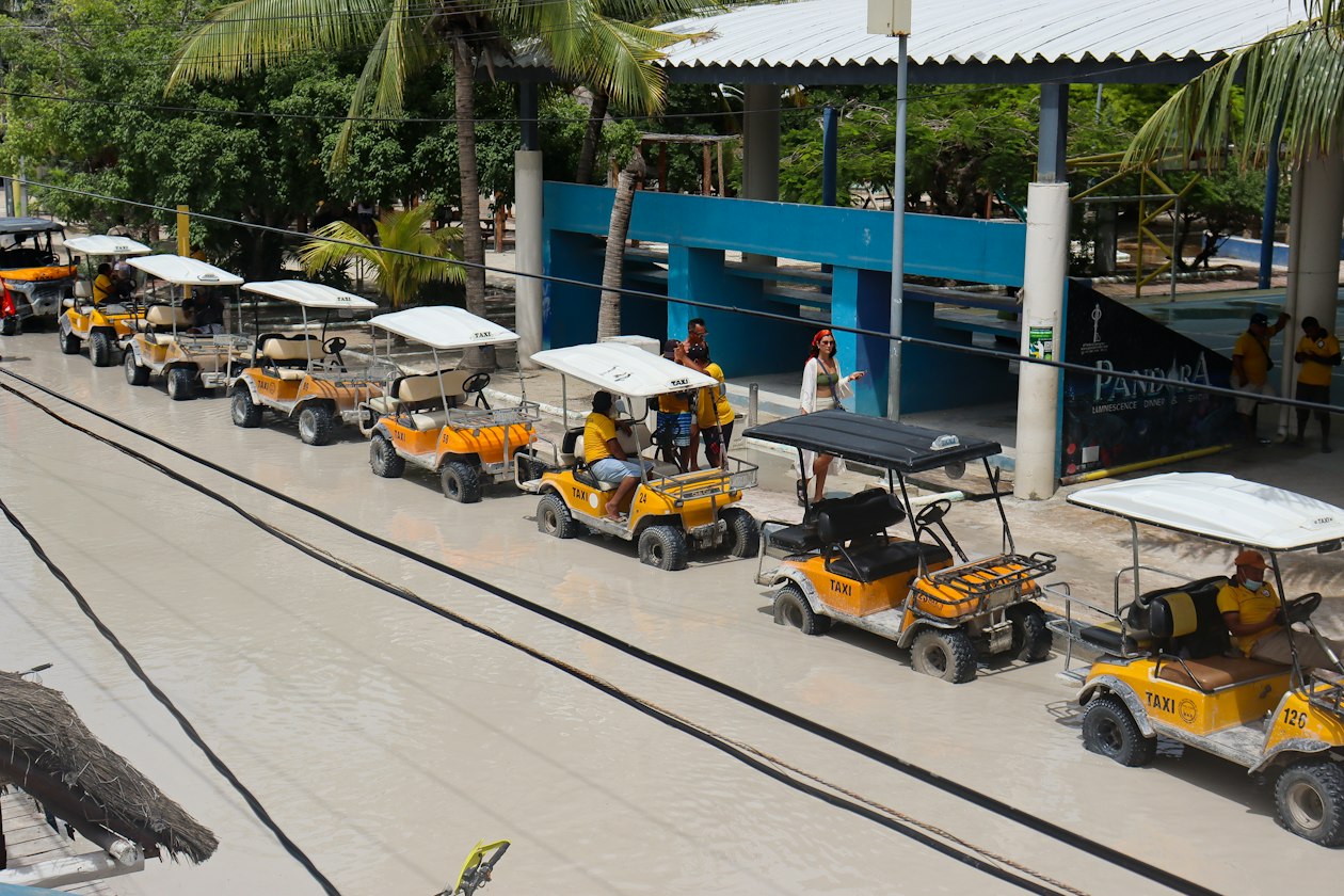 Row of golf-cart taxis on a wet sand street in Holbox, a car-free island that is worth it if you do not mind unpaved roads