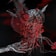 An intricate and surreal 3D rendering featuring a heart-like structure intertwined with wires and surrounded by abstract, organic forms. The metallic, horned surface gives a dark and futuristic vibe, while the rich red and black color scheme adds intensity. A metallic hand appears to cradle the main structure, amplifying the sense of an artificial, yet organic creation.