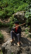 Close-up of hands gently playing a wooden flute surrounded by nature.