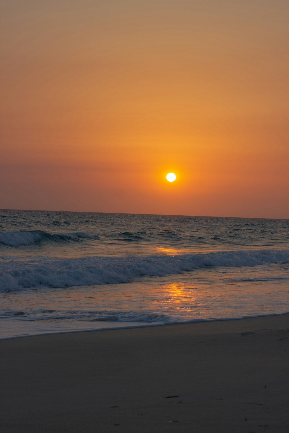 the sun is setting over the ocean on the beach