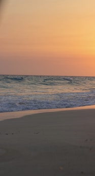 A serene beach scene at sunset with gentle waves and soft sand, evoking calm and tranquility.