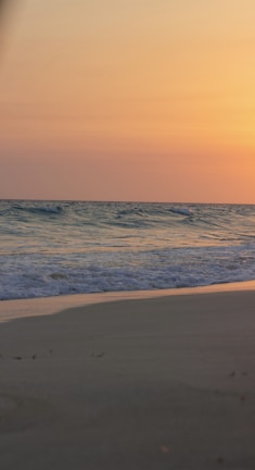 A serene beach at sunset with a family enjoying the calm waves.