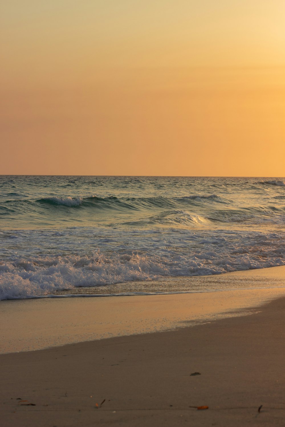 the sun is setting over the water at the beach