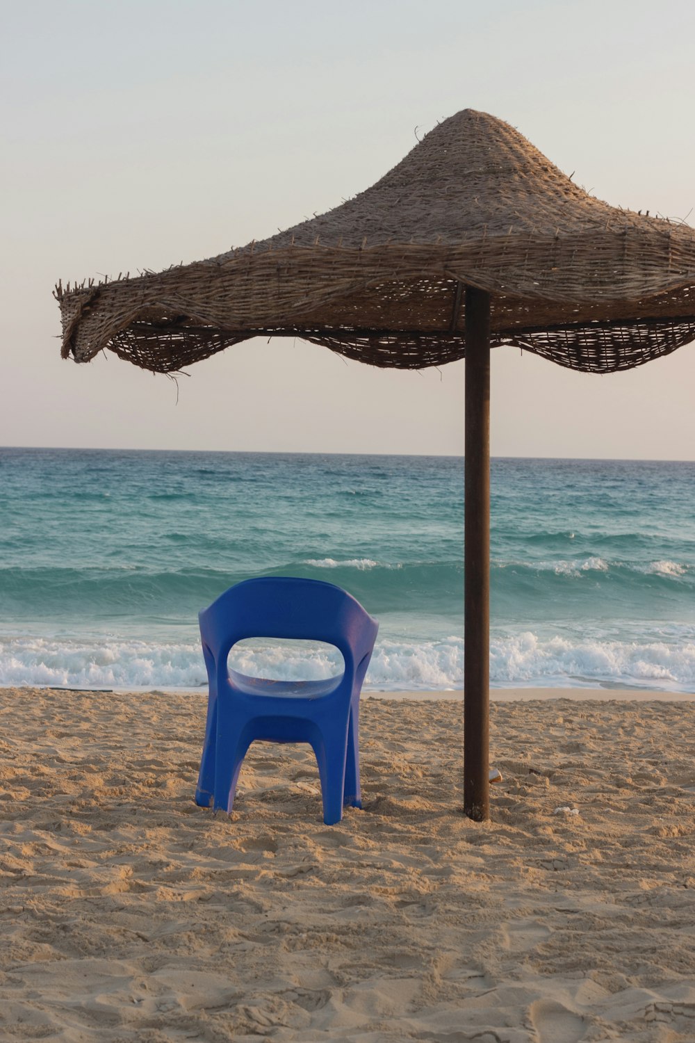 a blue chair sitting on top of a sandy beach