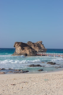 a sandy beach with a bridge and a body of water