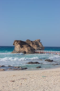 a sandy beach with a bridge and a body of water