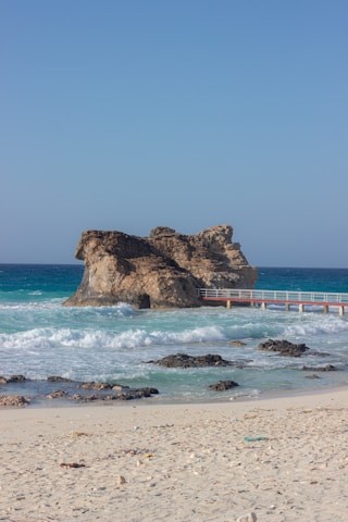 a sandy beach with a bridge and a body of water