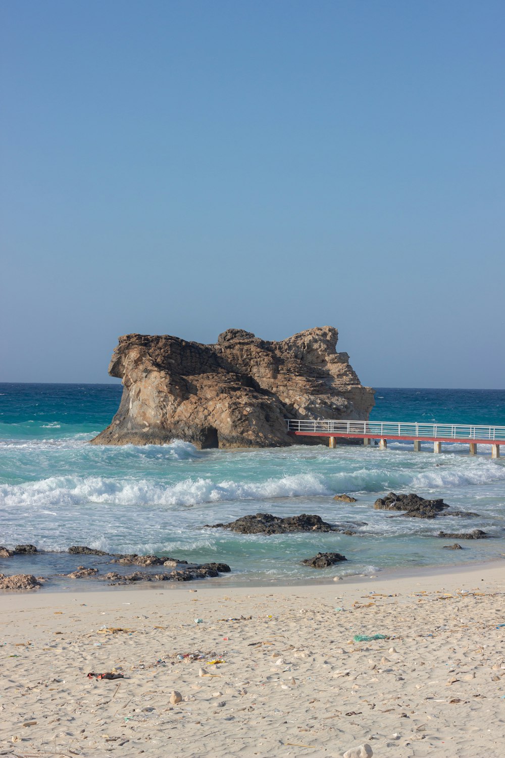 a sandy beach with a bridge and a body of water