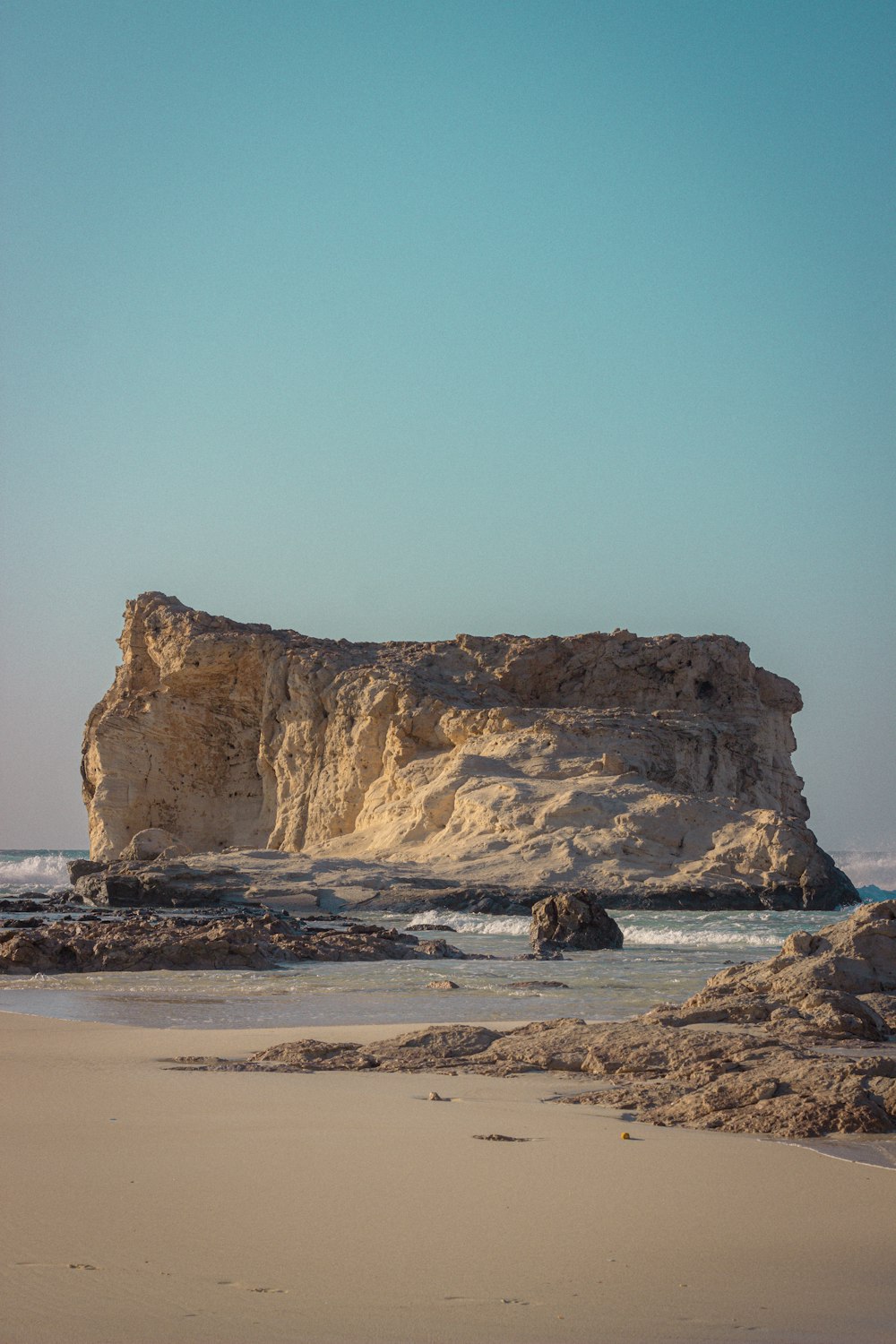 a large rock outcropping on a beach next to the ocean