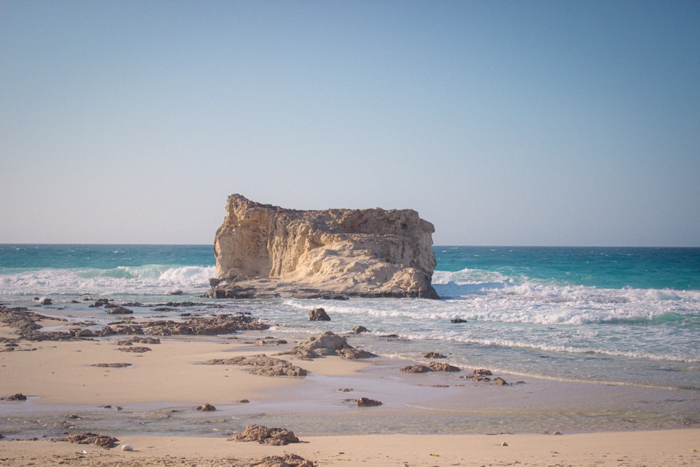 a large rock sitting on top of a sandy beach