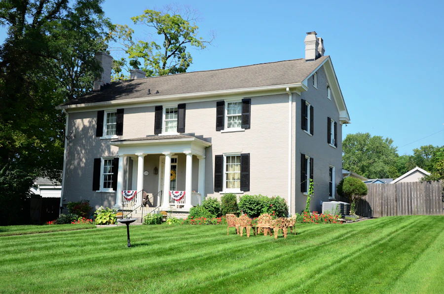 White colonial with black shutters and flag bunting above a freshly striped front lawn