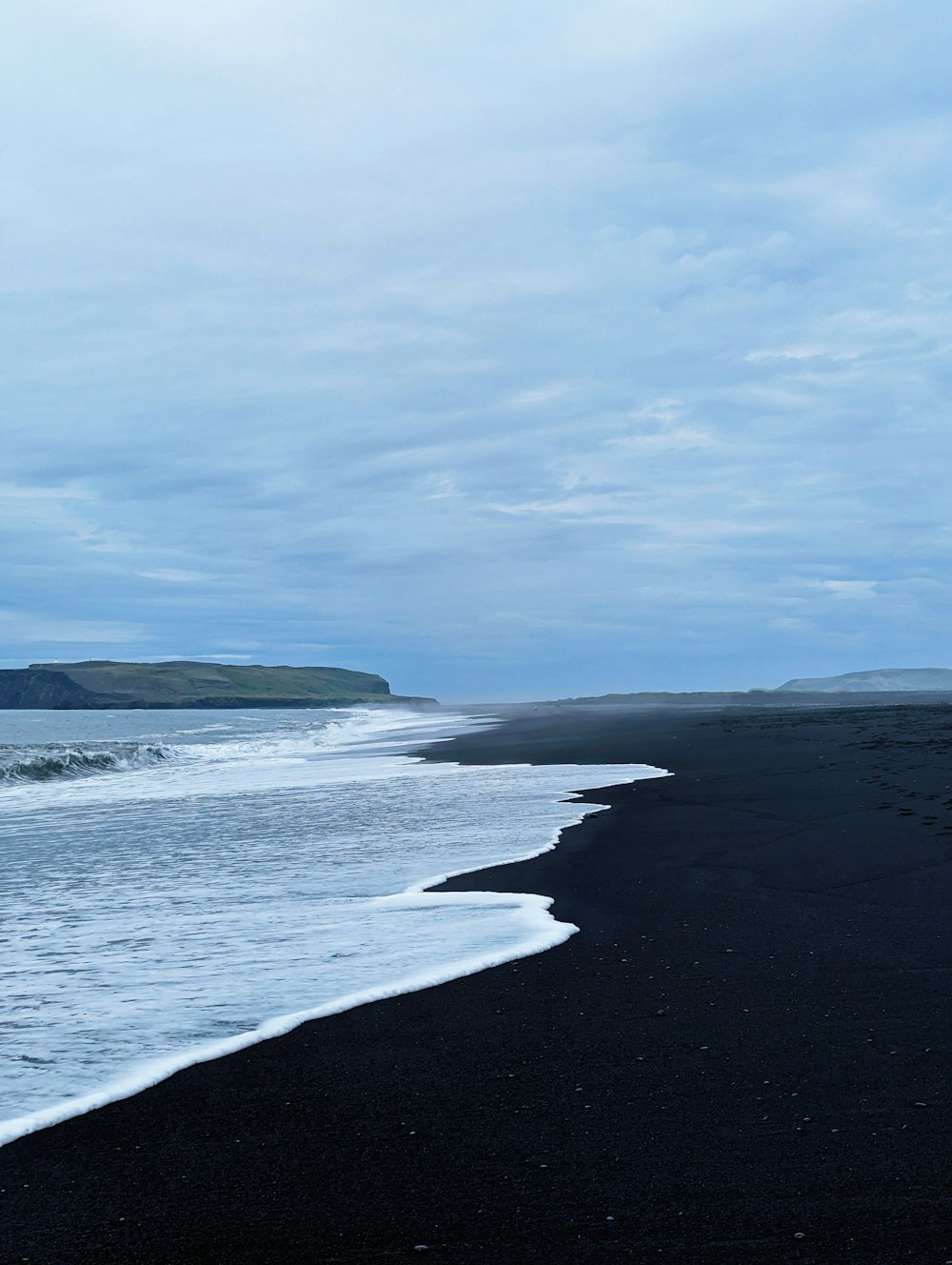 a black sand beach with waves coming in to shore