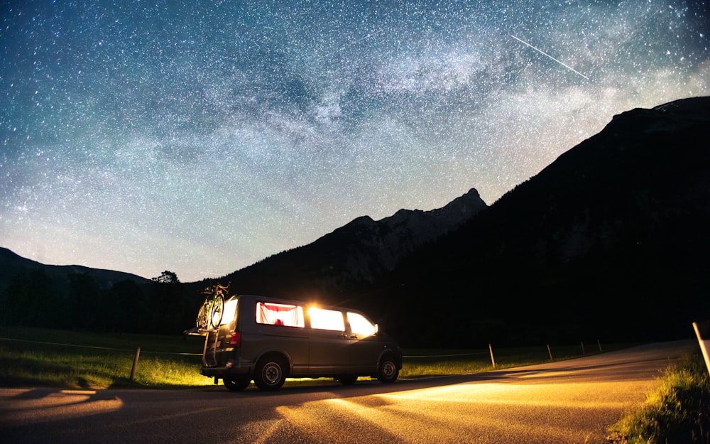 a van parked on the side of a road under a night sky filled with stars