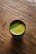 Close-up of a steaming cup of bright green matcha powder mixed with water.