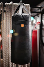 Dynamic shot of a boxer training with a Fabryka Ciosu punching bag in a bright gym.