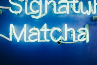 Bright neon sign spelling out 'Signature Matcha' against a vibrant blue background.