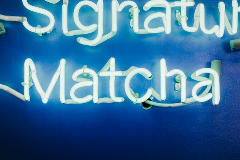 Bright neon sign spelling out 'Signature Matcha' against a vibrant blue background.