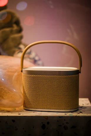 Sleek Bluetooth speaker glowing softly, set against a backdrop of a cozy living room ambiance