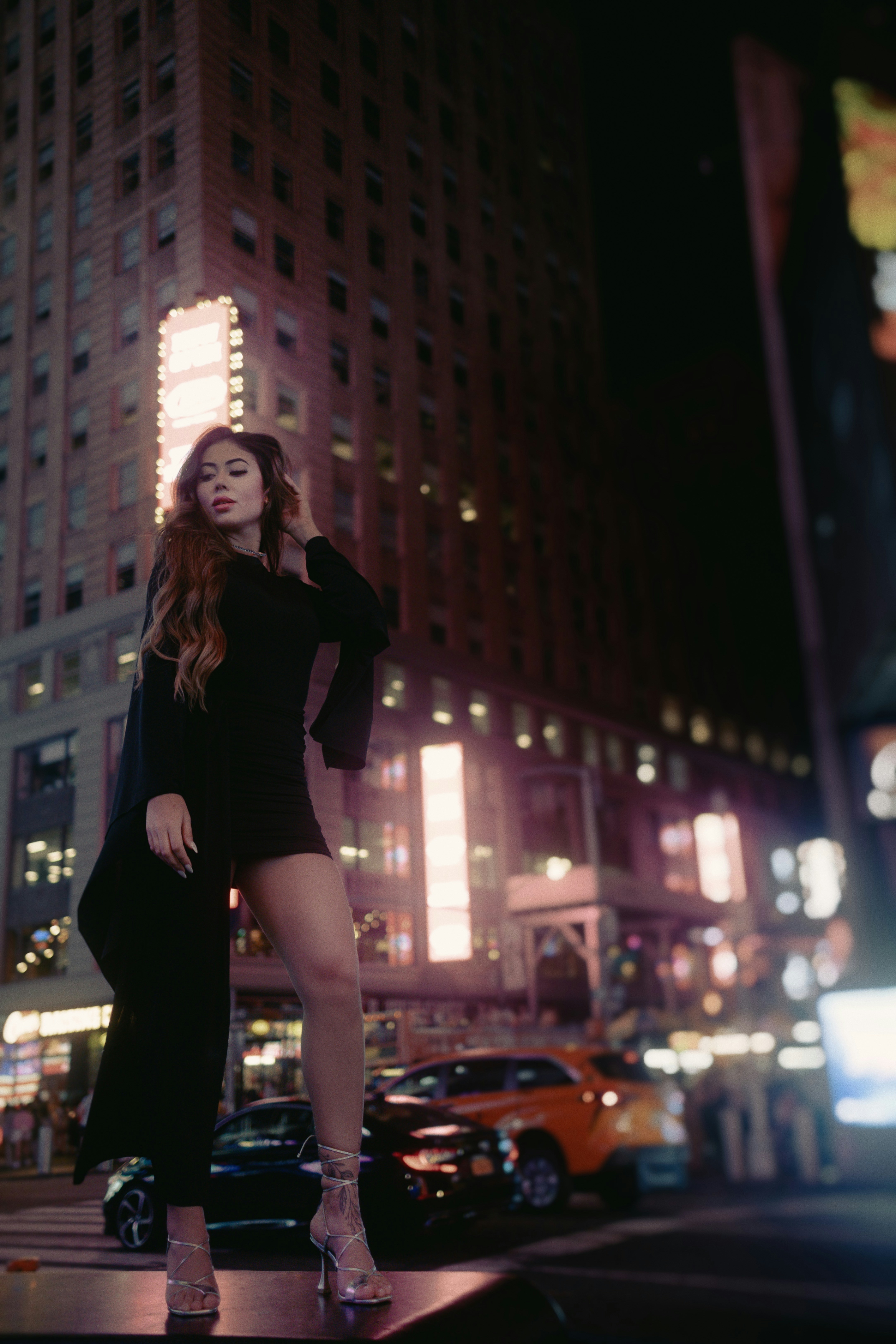 A woman in a short black dress standing on a city street photo – Free ...