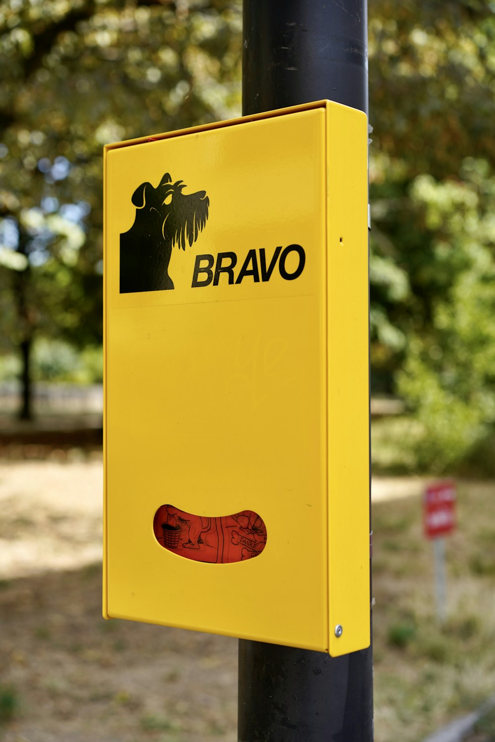 a yellow sign on a black pole in a park