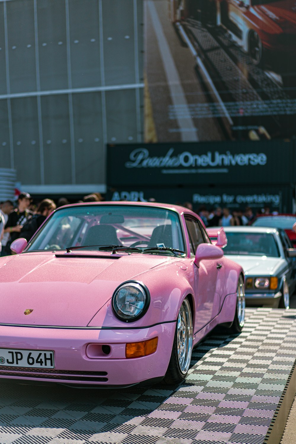 a pink porsche parked in front of a crowd of people