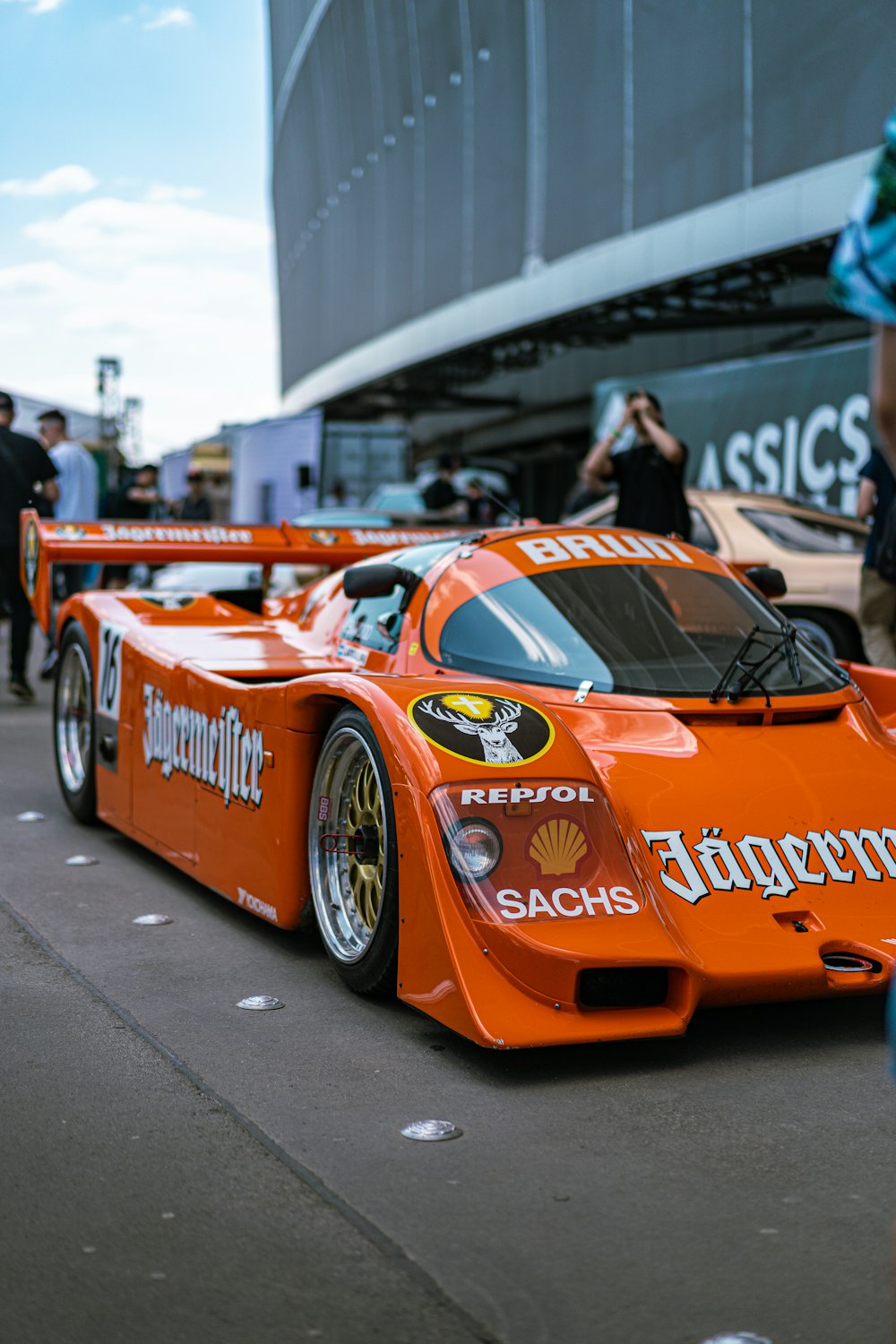 Ein orangefarbener Rennwagen parkt vor einem Gebäude