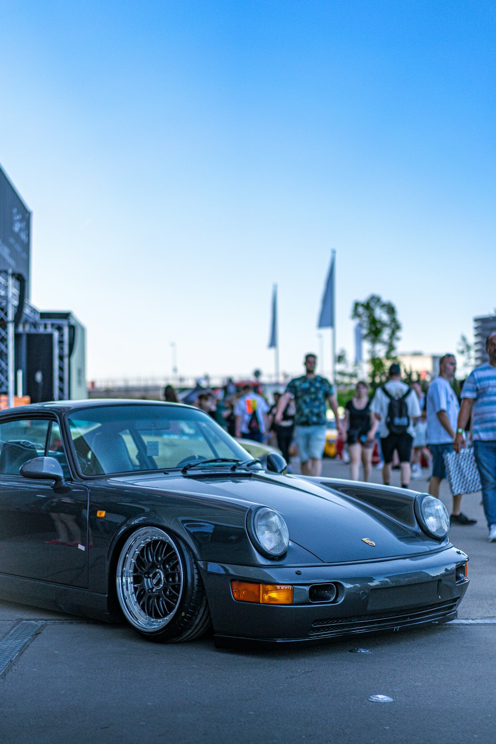 a black porsche parked in front of a crowd of people