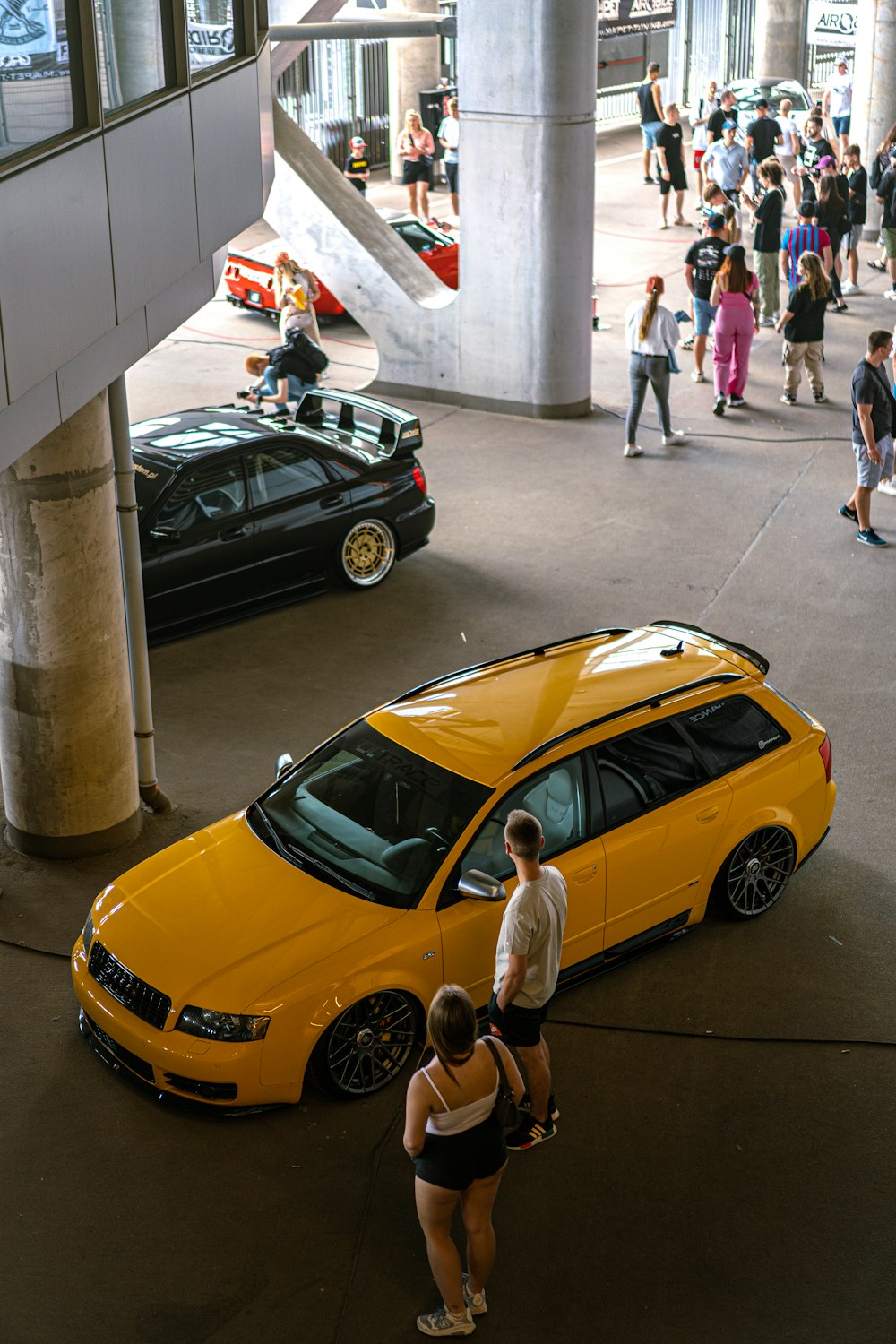 a group of people standing around a yellow car
