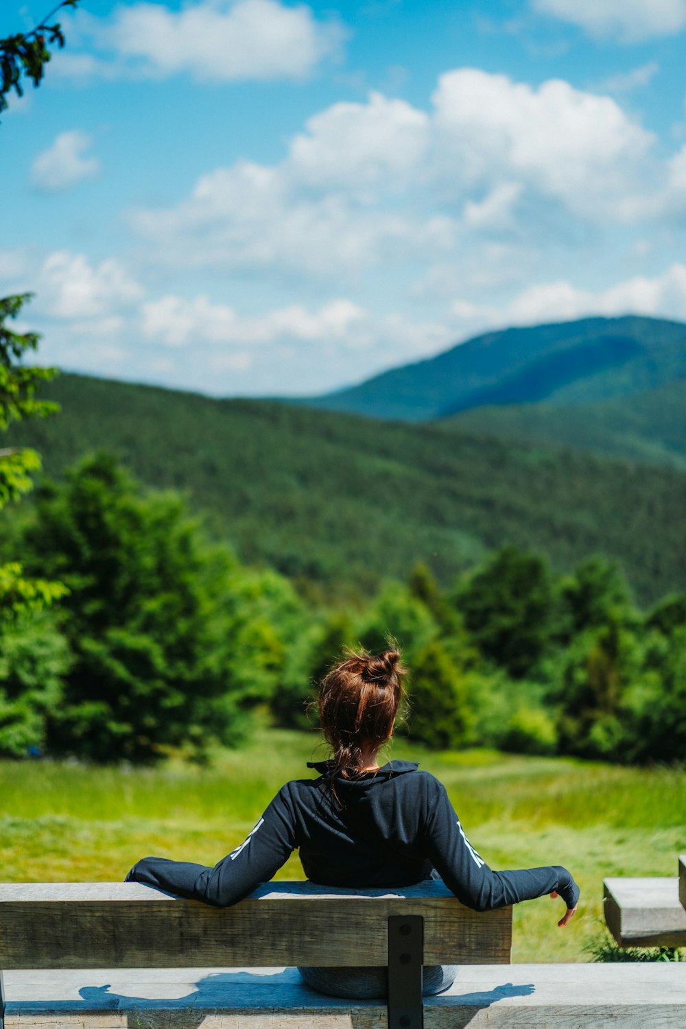 a woman is sitting on a bench in the mountains