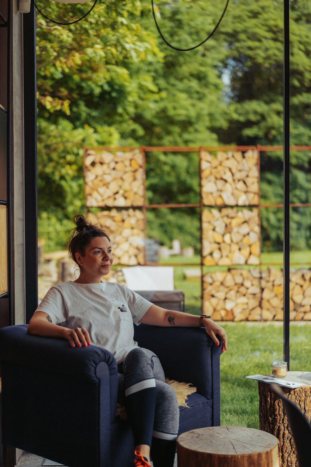 a woman sitting in a chair next to a tree stump